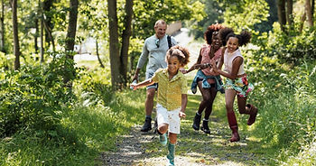 Family of four goes on a walk on a trail in the woods
