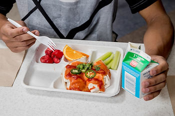 A child eats food from a school lunch tray