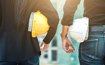 Two workers hold hard hats under their arms